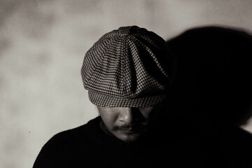 Asian man with mustache and beard and wearing scarf and newsboy hat poses close up. Detail of the...