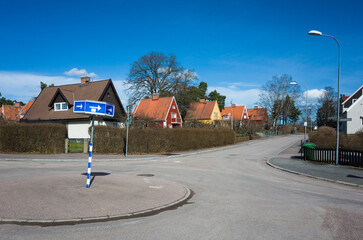 Quiet residential area in spring sunny day in Sweden, Empty street in Scandinavia, Roundabout road sign with white arrows on a blue background