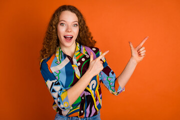 Photo of astonished nice woman girl wear trendy print clothes two arms introduce empty space isolated on vibrant orange color background