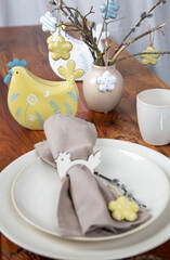 Gedeckter Tisch zu Ostern mit Hühner und Servietten in natürlichen Farben