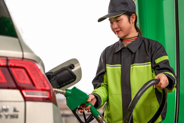 Asian gas station female employee using a gas pump to refuel a car
