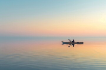 Minimalistic image of a kayaker paddling in calm waters during a soft-colored sunset