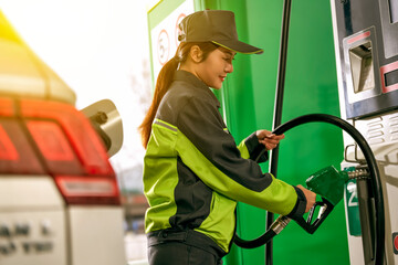 Asian gas station female employee using a gas pump to refuel a car