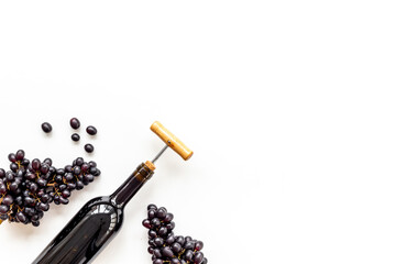 Obraz premium Red wine in the bottle with bunch of grapes and corkscrew, top view