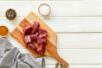 Raw beef meat cutting into pieces on wooden board with spices