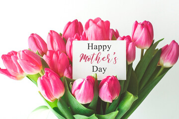 a bouquet of beautiful pink tulips and a white gift card with the inscription Happy Mother's Day, sweet wish concept