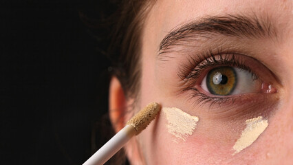 Close-Up Shot Of A Girl Applying Concealer Under Her Eyes And Makeup Foundation On Her Eyelids