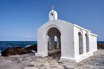 A white Orthodox chapel on a stone headland in the town of Georgioupoli on the island of Crete