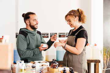 Woman Sampling Beauty Cream at a Zero-Waste Grocery Store With Assistance From Male Attendant
