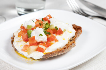 Frisella or Fresella typical south italian bread, Typical southern Italian bread. Frisella seasoned with olive oil, burrata buffalo mozzarella, cherry tomatoes and basil