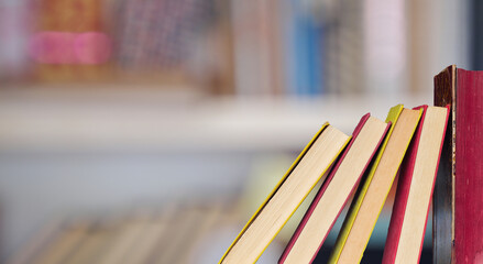 row of books against blurred bookshelf background.Book fair, inspiration,reading, education,...