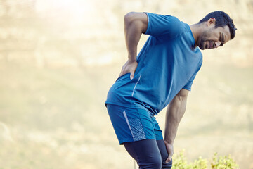 Fototapeta premium Health, fitness and man with back injury from running training or practice outdoor in nature. Asian male person and athlete with muscle pain and aching body from workout for medical emergency