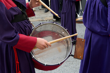 Musicians playing drums during a procession. They are dressed in colorful robes that create a...