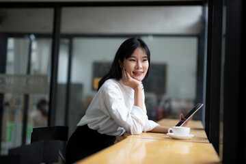 Engaged businesswoman using a digital tablet in a cozy coffee shop setting with a fresh cup of coffee on the table.