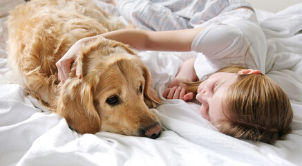 Sweet Little Girl Gently Petting Her Charming Golden Retriever Dog While Lying In Bed With Her Beloved Pet