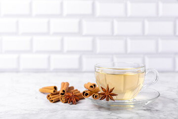 Fragrant hot tea with cinnamon stick and anise on a textured wooden background. A cup of hot tea with honey, lemon, mint and apples. Spicy tea with spices. Immunity tea. Health concept.Copy space.