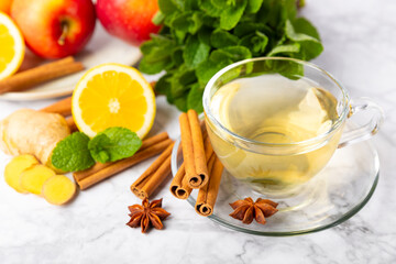 Fragrant hot tea with cinnamon stick and anise on a textured wooden background. A cup of hot tea with honey, lemon, mint and apples. Spicy tea with spices. Immunity tea. Health concept.Copy space.