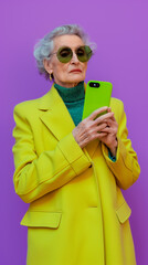 Stylish elderly woman with smartphone, trendy purple and green. Concept of fashion for seniors, technology use in older age, active lifestyle