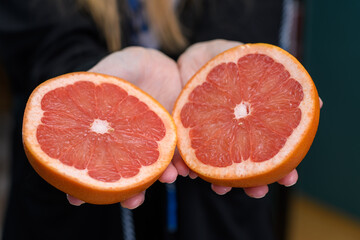 Grejpfrut przekrojony na dwie równe połowy trzymany w dłoniach  © Paweł Kacperek