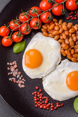 English breakfast with fried eggs, bacon, beans, tomatoes, spices and herbs