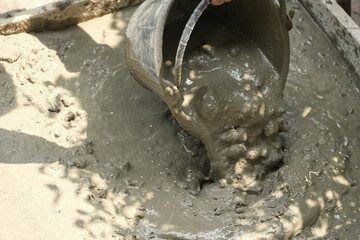 Worker pours out of a bucket liquid mixing cement mortar on the floor.