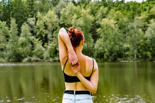 Back view of fitness slender fit girl woman practicing doing yoga gomukhasana,holding hands behind back,stretching in Cow Face Pose,river,relaxing.nature landscape.Triceps arms training