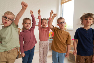 Preschool children with hands raised