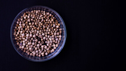 organic pepper dried white pepper corns in Indonesian in traditonal asian glass bowl on black background