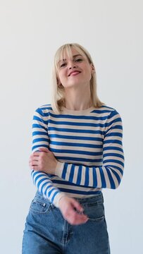Portrait of a cheerful, carefree, delighted Caucasian woman with crossed arms on white background. Relaxed, optimistic, satisfied lady. Vertical video.