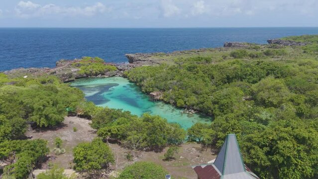 Weekuri Lagoon, Sumba island, Indonesia. A beautiful blue lake with a green forest in the background. The water is calm and clear, and the trees are lush and green