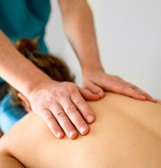 Girl during massage for neck and shoulders in spa clinic salon. Masseur hands doing care body therapy procedure for young woman wellness and relaxation.