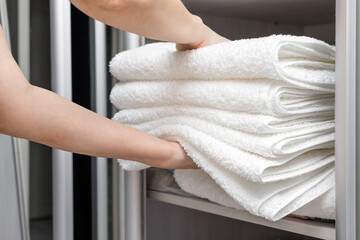 woman putting white towels in the closet