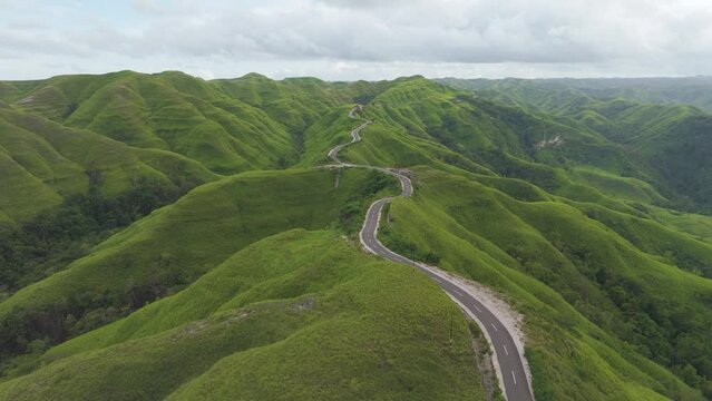 Sumba, Indonesia. Aerial view of a long country road leading to the coast with a view of beautiful green hills. 