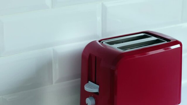Roasted toast bread popping up from bright red toaster machine. Two toast pieces popping out from toaster 