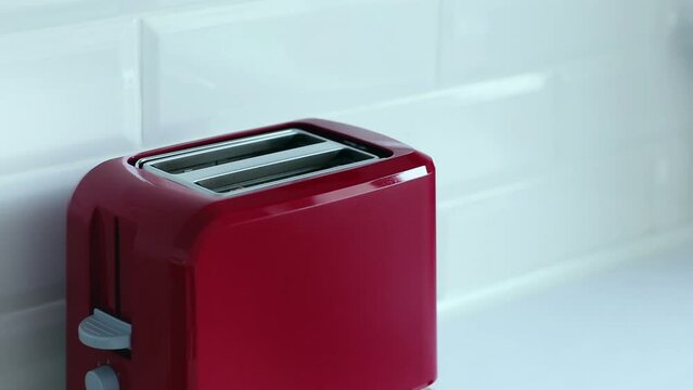 Roasted toast bread popping up from bright red toaster machine. Two toast pieces popping out from toaster 