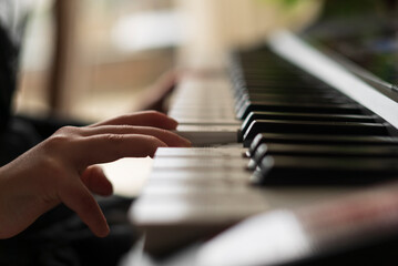 Close-up of a woman's hand playing on a piano.