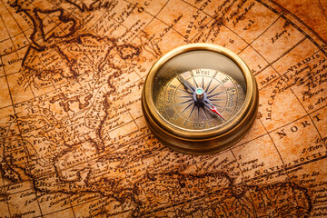 Vintage still life. Vintage compass lies on an ancient world map of 1565. Vintage style travel and adventure.