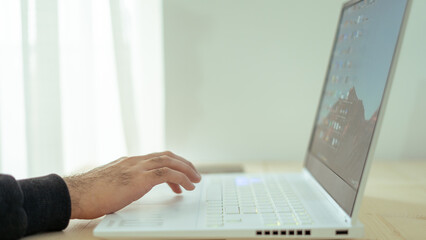 Businessman using laptop computer at home. Close up of male hands typing on laptop keyboard in...