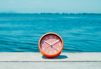 clock on a wooden pier next to the water - 796604032
