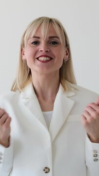 Portrait of a Caucasian woman blogger talking with audience in online social media during broadcast, standing on white background. Vertical video.