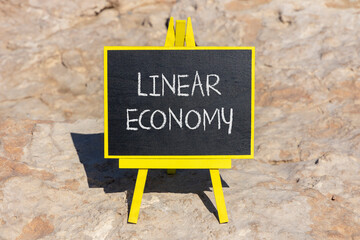 Linear economy symbol. Concept words Linear economy on beautiful black blackboard. Beautiful stone...