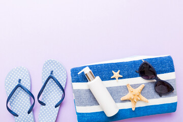 Summer holiday concept. Top view of beach towel, flip flop and sunscreen cream on table Top view with copy space for text - obrazy, fototapety, plakaty