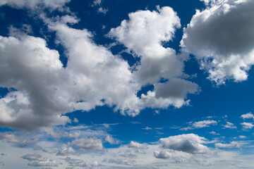 Clouds on a clear and sunny day with white cloud formations, hidden sun and deep blue sky. Wide...