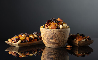Mix of various nuts and raisins on a black reflective background.