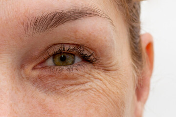 Close up cropped eye with wrinkles of middle aged caucasian woman looking at camera
