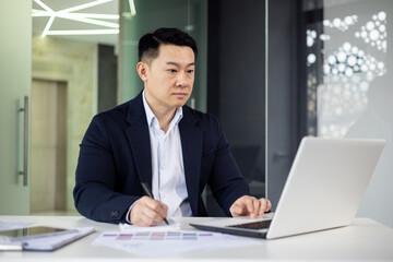 Focused businessman working on laptop in modern office