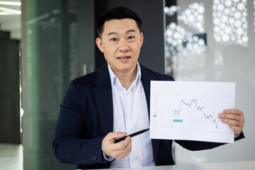 Confident businessman presents financial chart in modern office