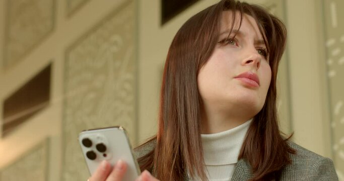 Portrait of young woman waits anxiously for a meeting. Punctuality was agreed upon, but it has been breached, leaving the woman feeling concerned. Minutes tick by, young woman's anxiety intensifies.