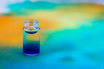 Glass bottle with blue ink on background with color stain