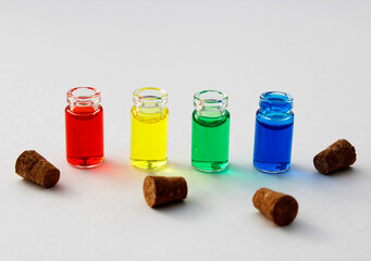 Bottles with red, yellow, green and blue ink next to their corks